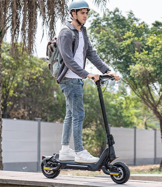 A young man wearing a helmet is riding a Todimart-X5s electric scooter: a black Todimart-X5s electric scooter (equipped with durable tires) – casual attire, outdoor setting – perfect for city commuting