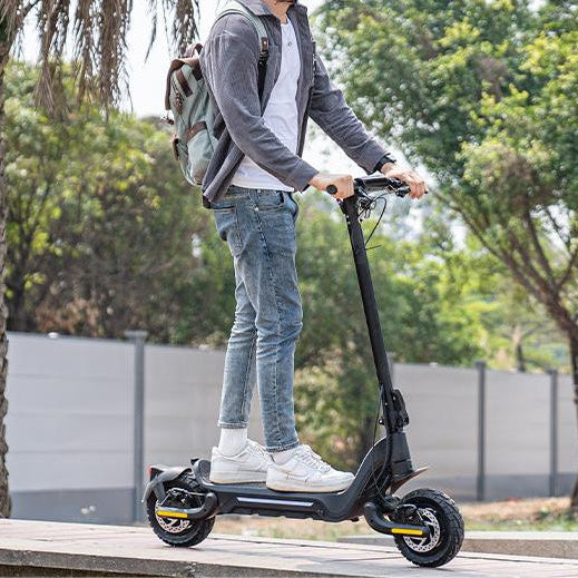 A young man wearing a helmet is riding a Todimart-X5s electric scooter: a black Todimart-X5s electric scooter (equipped with durable tires) – casual attire, outdoor setting – perfect for city commuting
