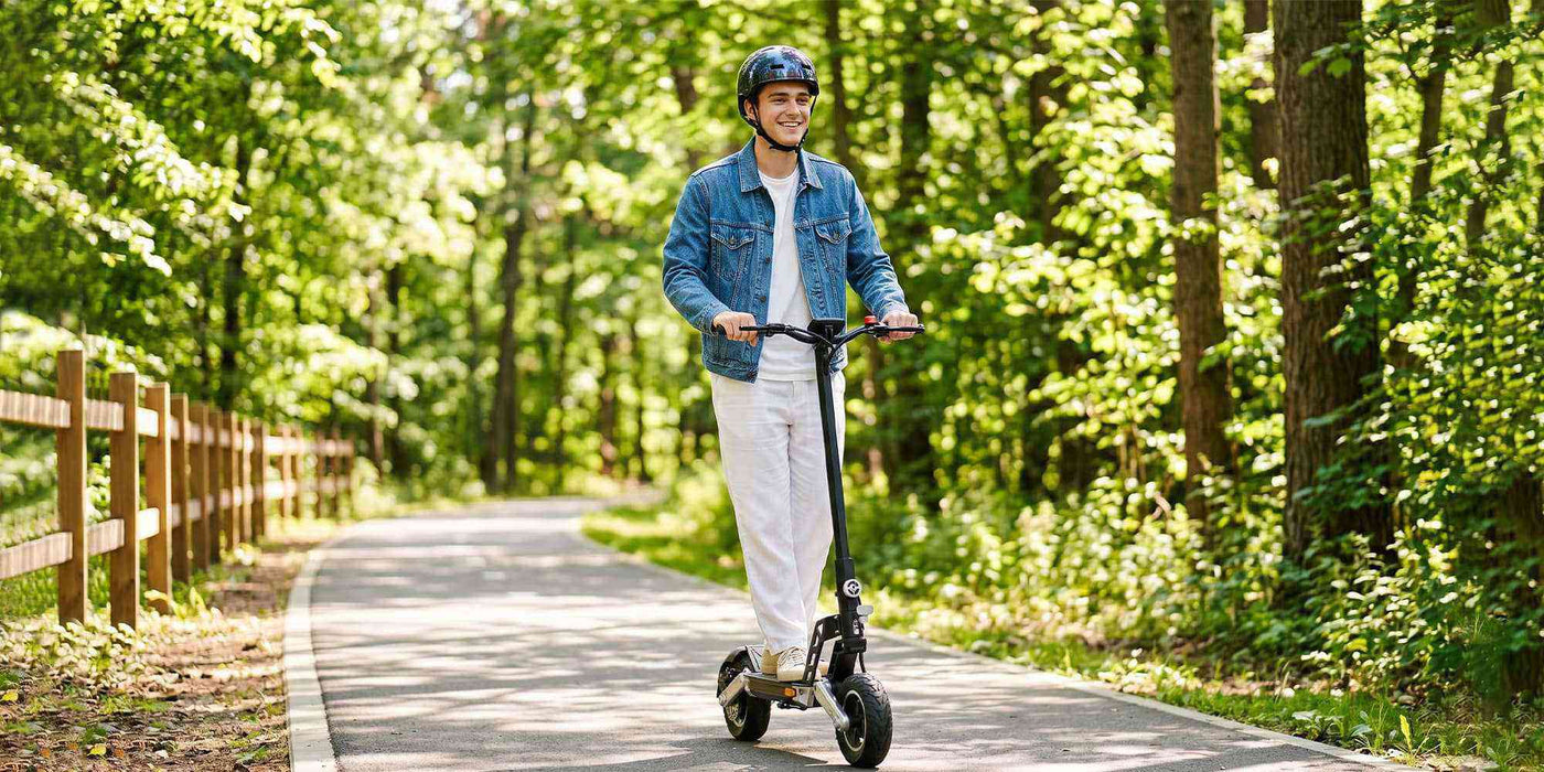 A young man wearing a helmet on a Todimart-G2ABE electric scooter: Black Todimart-G2ABE electric scooter (rugged tires) - casual wear, outdoor setting - perfect for city commuting.