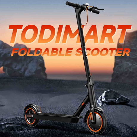 The TODIMART folding scooter stands firmly on the rough, gravelly ground, the clearly visible pebbles and particles instantly showcasing its off-road capabilities. The backdrop is an open, rustic outdoor environment—perhaps a dry trail or the edge of a construction site—with soft, natural tones and a light dust in the air. The scooter itself maintains a clean, folding design, while the rugged terrain underfoot highlights its durability, grip, and all-terrain capability. Soft sunlight casts short, sharp shad