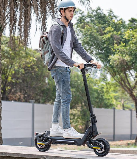 A young man wearing a helmet is riding a Todimart-X5s electric scooter: a black Todimart-X5s electric scooter (equipped with durable tires) – casual attire, outdoor setting – perfect for city commuting